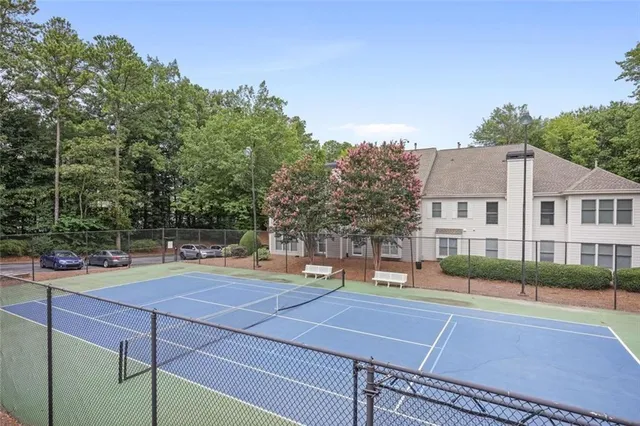 a view of a tennis ground with large trees