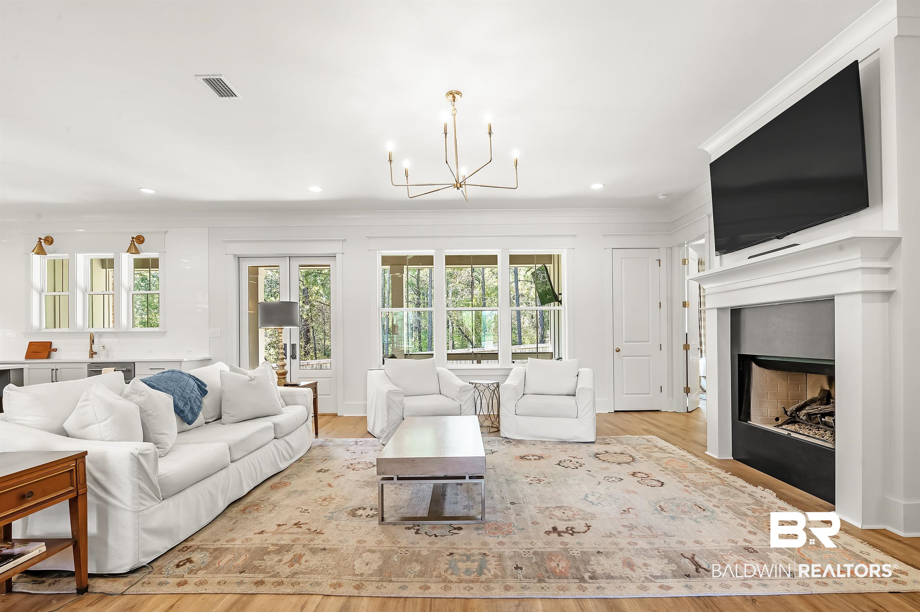 27888 Oakachoy Loop Daphne, AL 36526 - Photo 14 of 65 Living area featuring crown molding, light wood-type flooring, visible vents, a notable chandelier, and a fireplace