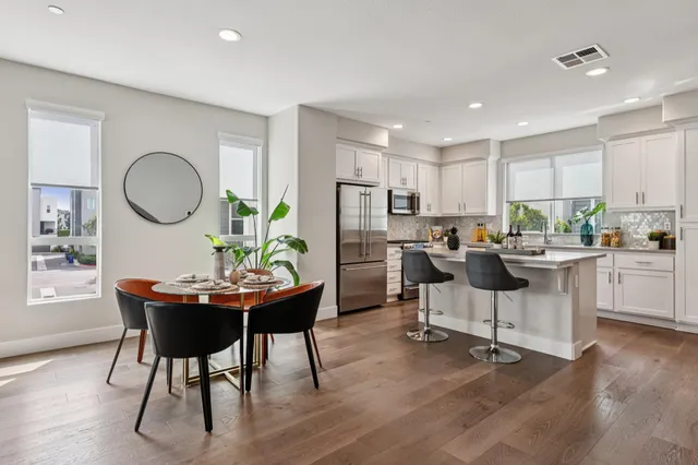 a living room with stainless steel appliances kitchen island granite countertop furniture and a wooden floor