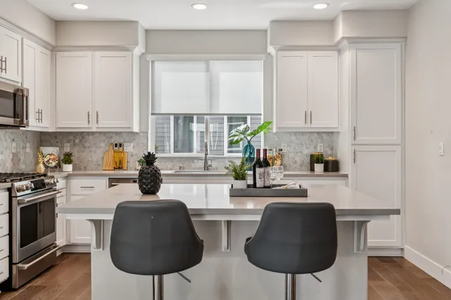 a kitchen with stainless steel appliances a stove a sink cabinets and a window