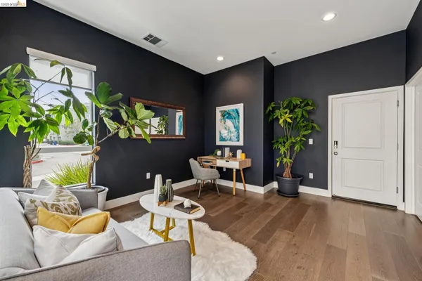 a living room with furniture a potted plant and a wooden floor