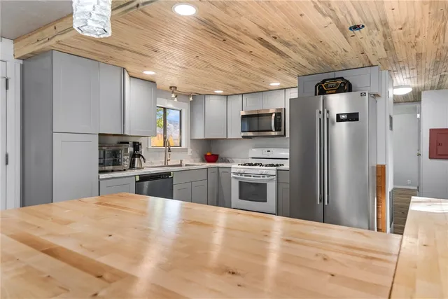 a kitchen with stainless steel appliances a refrigerator a stove a sink dishwasher a oven with a dining table and chairs