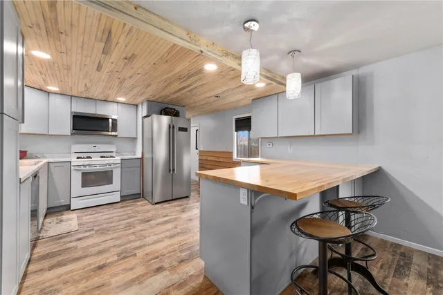 a kitchen with stainless steel appliances granite countertop a sink a stove a refrigerator cabinets and chairs