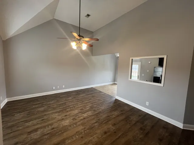 an empty room with wooden floor chandelier and window