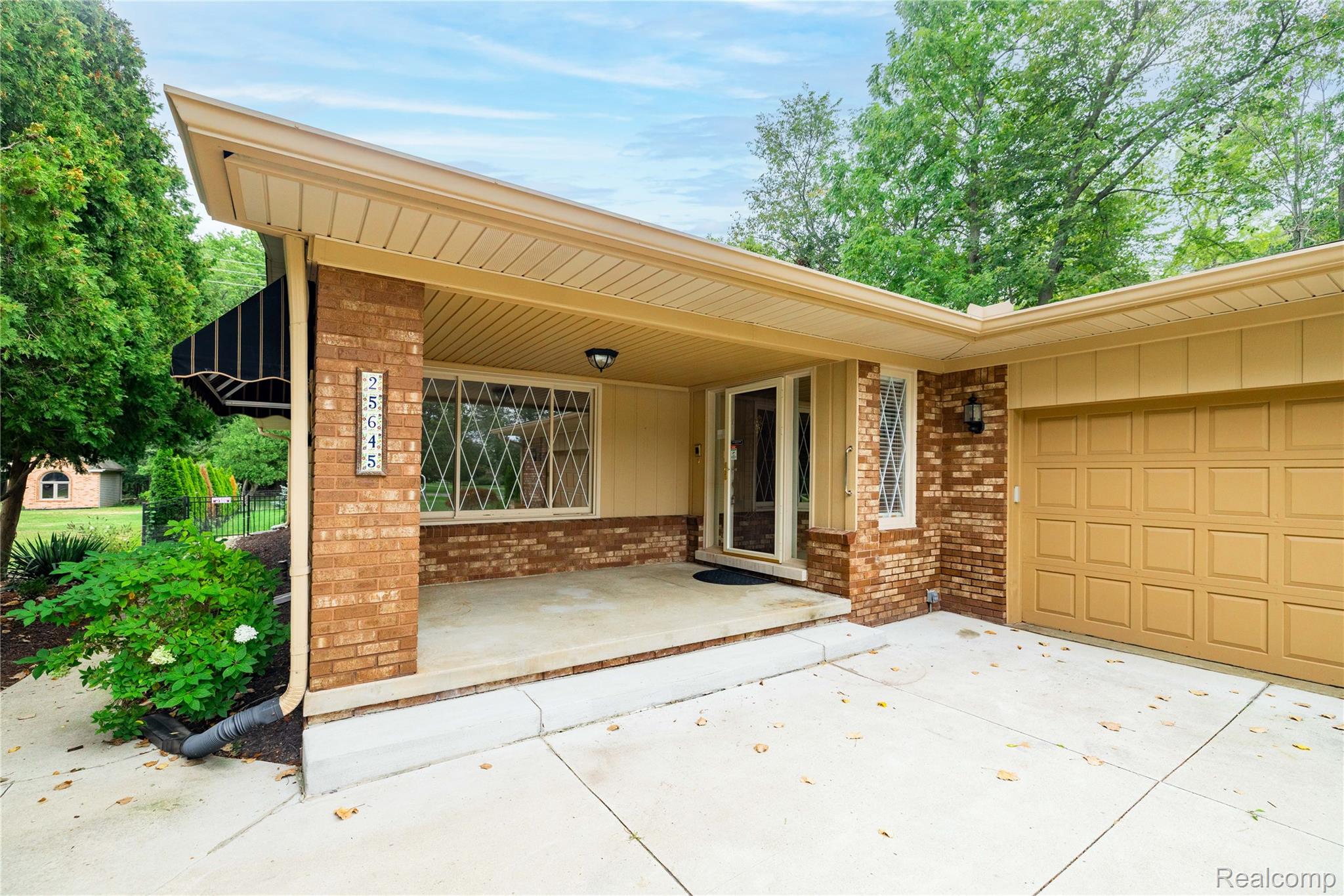 25645 Meridian Road Grosse Ile, MI 48138 - Photo 3 of 46 Brick exterior with a covered entry, an attached garage, and a concrete driveway