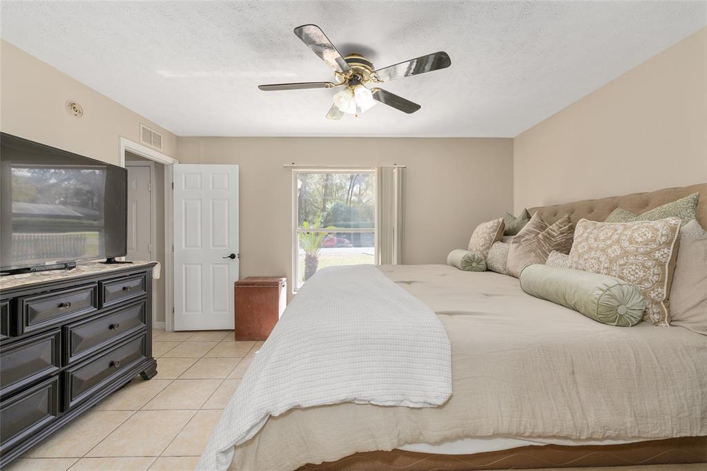 5255 Northwest 64 Street Ocala, FL 34482 - Photo 15 of 24 a spacious bedroom with a bed and a flat screen tv
