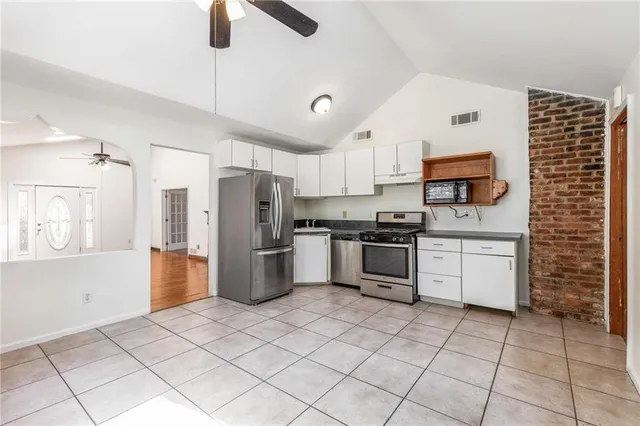 a view of an empty room with chandelier fan and wooden floor
