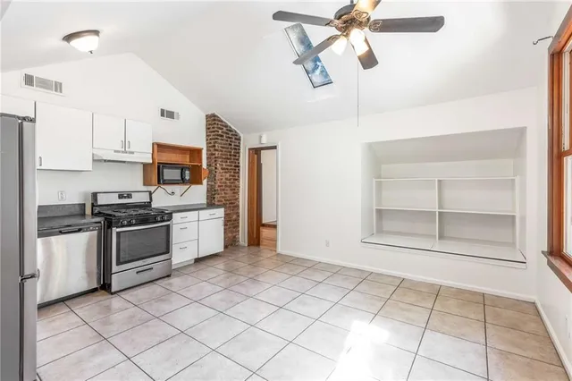 an empty room with wooden floor ceiling fan and window