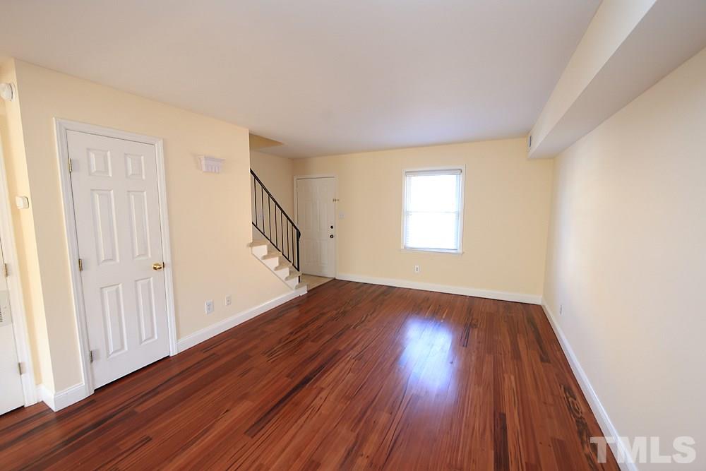 149 Jones Franklin Road, Unit H Raleigh, NC 27606 - Photo 3 of 12 an empty room with wooden floor and windows