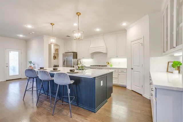 a kitchen with stainless steel appliances granite countertop a table chairs sink and white cabinets