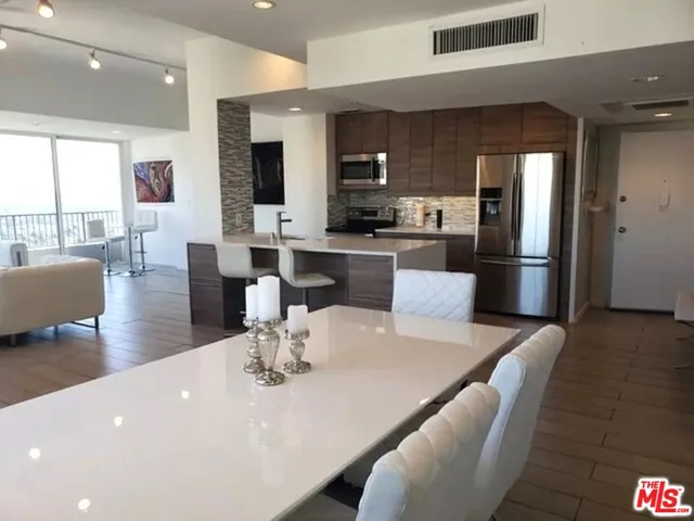 a large kitchen with stainless steel appliances a dining table chairs and a large window