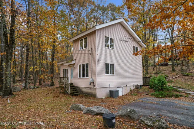 a view of a white house next to a yard with big trees