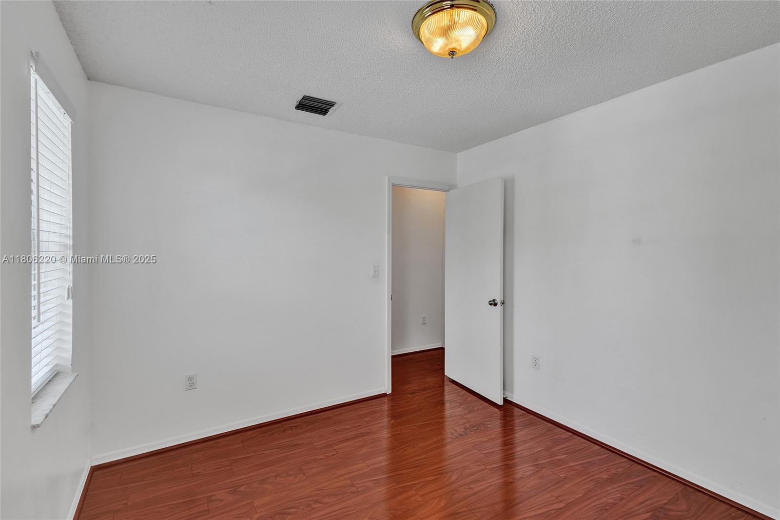 3910 Fern Forest Road Cooper City, FL 33026 - Photo 24 of 38 a view of an empty room with wooden floor and a window