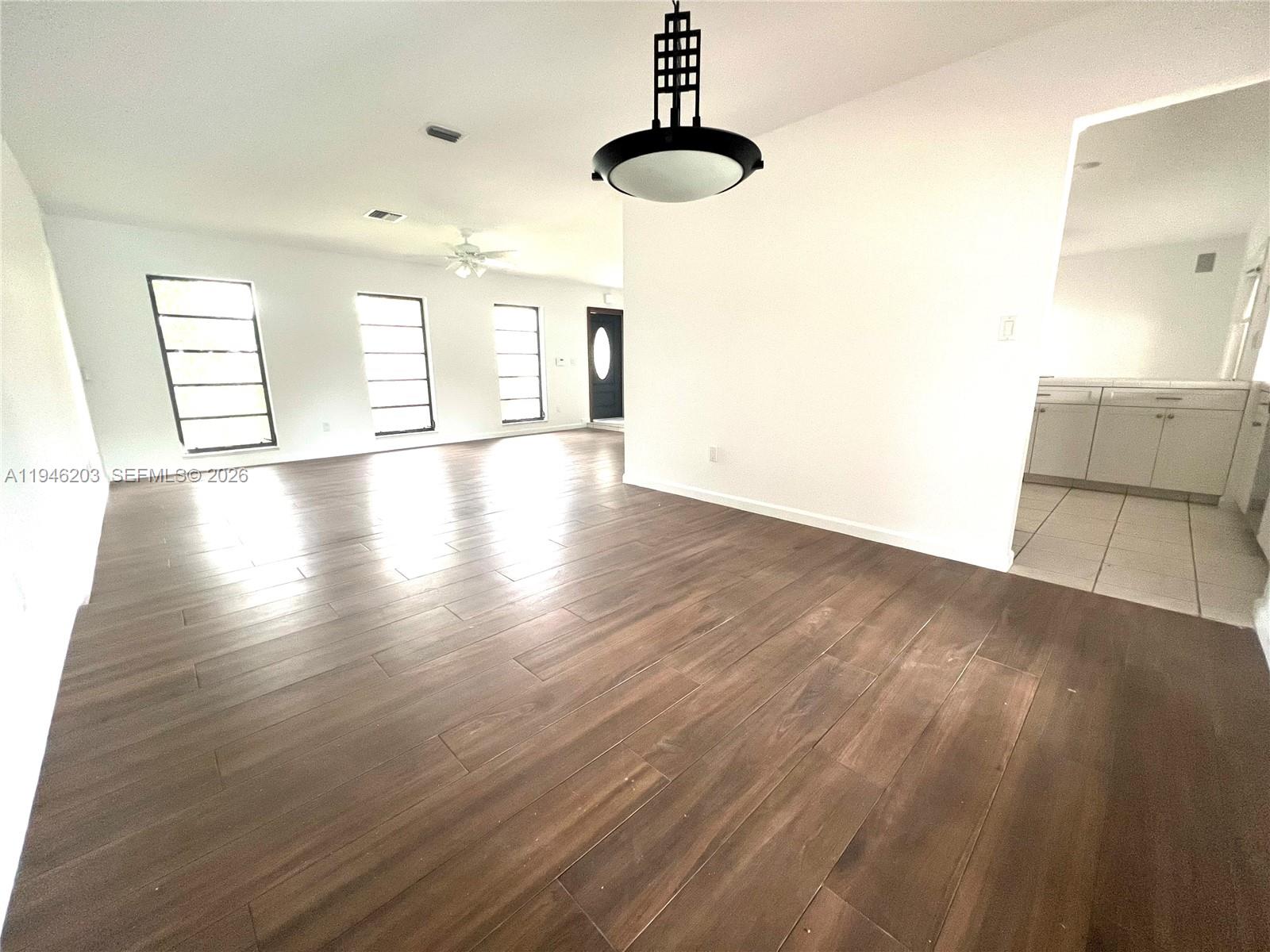 13100 Southwest 108th Place Miami, FL 33176 - Photo 3 of 16 a view of a room with wooden floor chandelier and windows