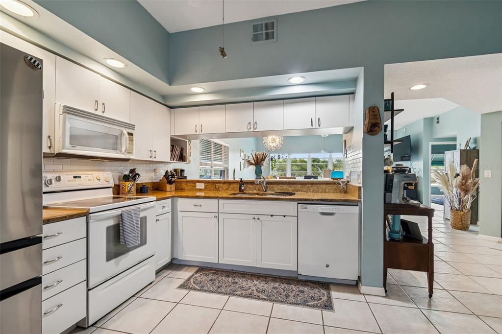 6499 99th Way North, Unit 18B St. Petersburg, FL 33708 - Photo 13 of 98 a kitchen with stainless steel appliances granite countertop a refrigerator and a stove top oven