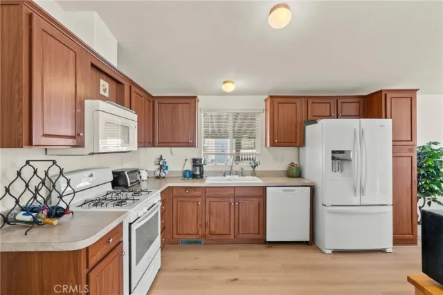 a kitchen with stainless steel appliances granite countertop a refrigerator a sink dishwasher and wooden cabinets with wooden floor