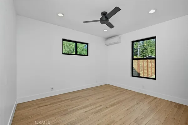 a view of empty room with wooden floor and ceiling fan