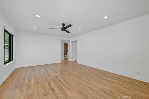a view of empty room with wooden floor and fan