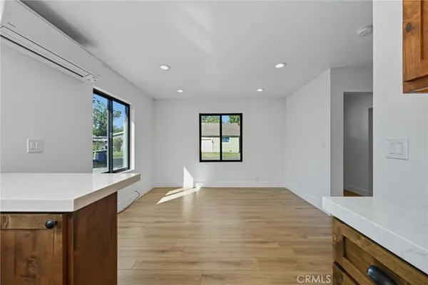 a view of an empty room with window and wooden floor