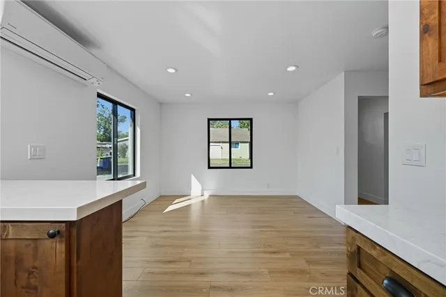 a view of an empty room with window and wooden floor