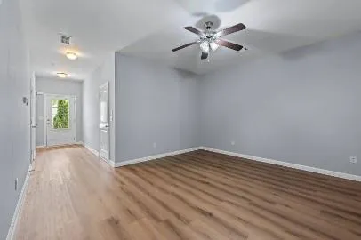an empty room with wooden floor and chandelier fan