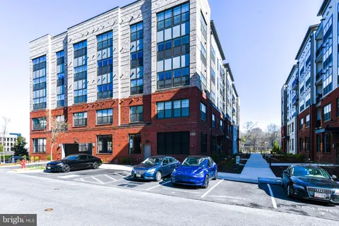 a front view of a building with lot of cars and trees