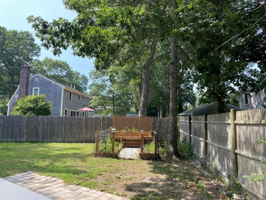21 Mashpee Neck Road Mashpee, MA 02649 - Photo 5 of 17 a view of a backyard with wooden fence and a large tree