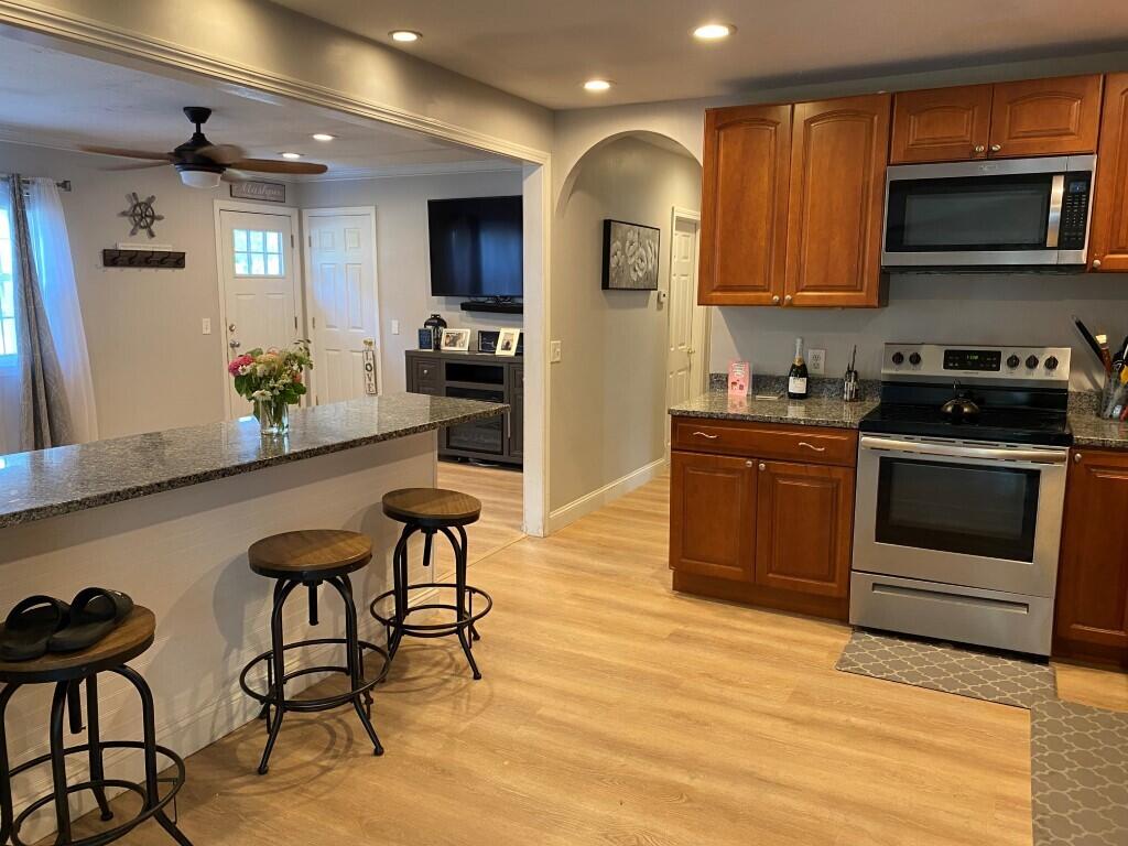 21 Mashpee Neck Road Mashpee, MA 02649 - Photo 6 of 17 a kitchen with stainless steel appliances kitchen island granite countertop a stove a sink and a microwave