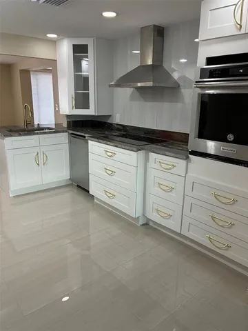 a kitchen with granite countertop white cabinets and stainless steel appliances