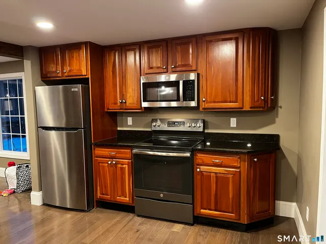 a kitchen with granite countertop wooden cabinets stainless steel appliances and a window