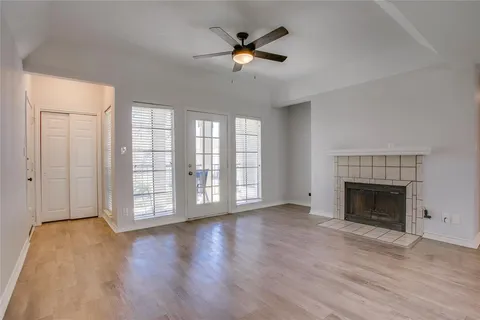 an empty room with wooden floor fan and windows