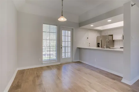 a view of an empty room with window and wooden floor