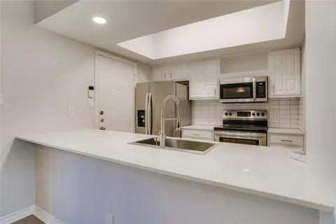 a kitchen with stainless steel appliances a refrigerator and a stove top oven
