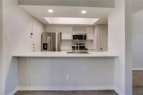 a kitchen with stainless steel appliances a sink a microwave a refrigerator and cabinets
