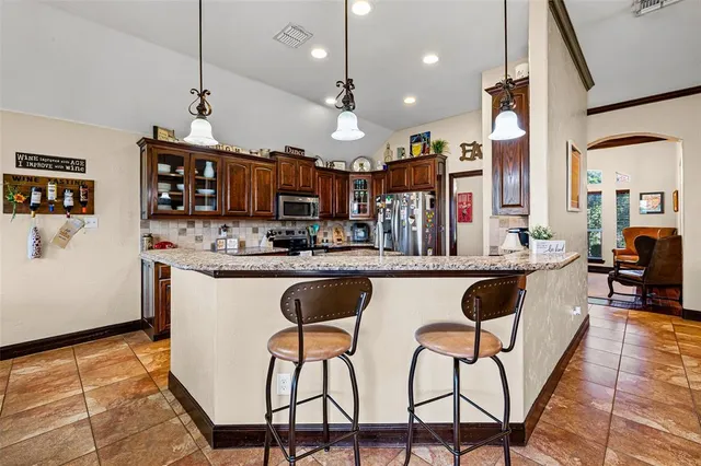 a kitchen with stainless steel appliances granite countertop a kitchen island a stove a cabinets a sink and a chairs