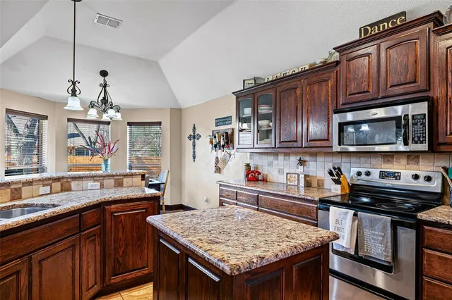 a kitchen with stainless steel appliances granite countertop a kitchen island a stove a sink dishwasher and microwave with wooden floor