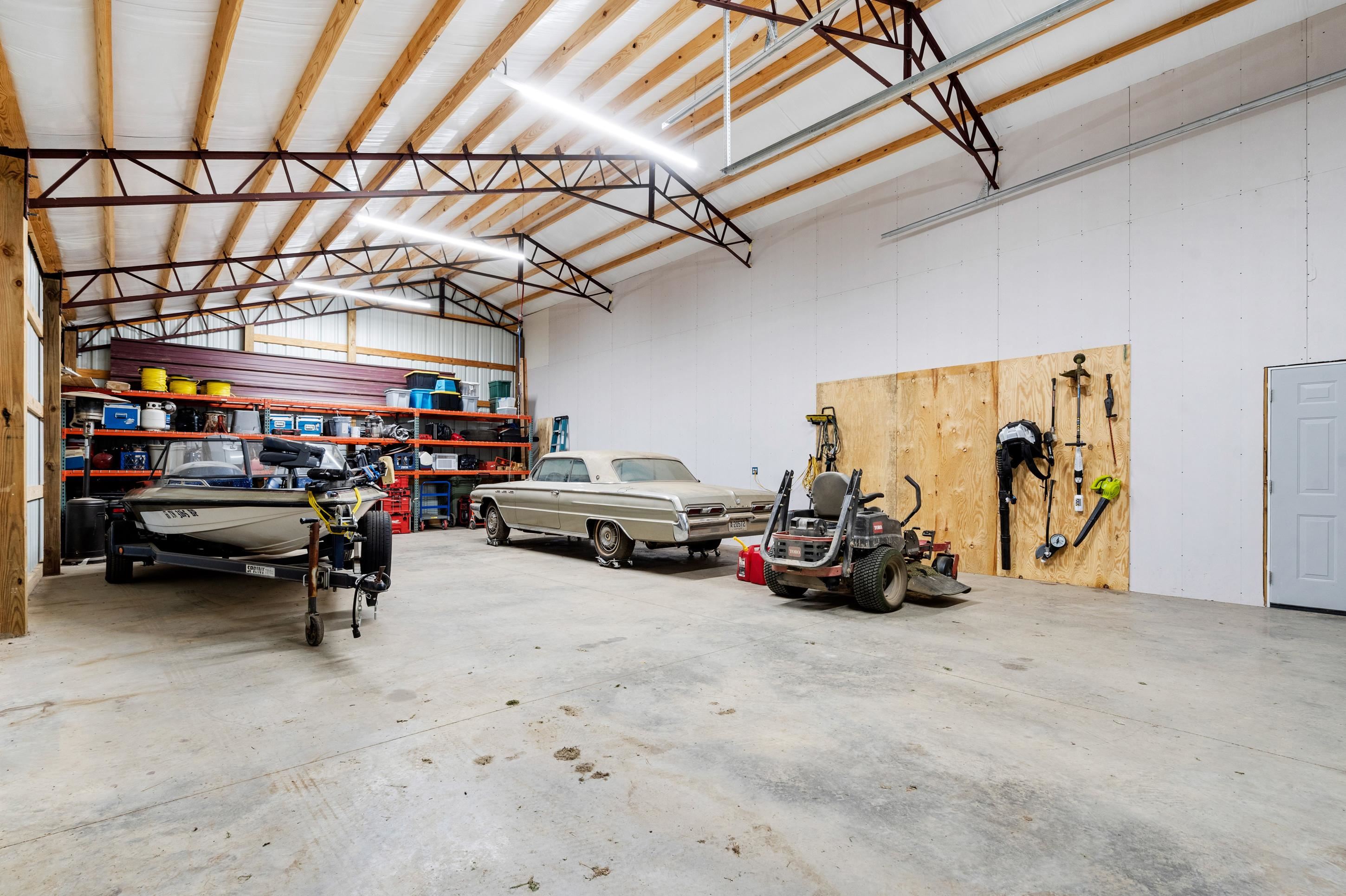 7757 Brunswick Road Millington, TN 38053 - Photo 36 of 40 Spacious garage with high ceilings, exposed trusses, concrete flooring, and ample storage shelving