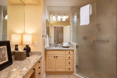 a bathroom with a granite countertop sink a mirror and a shower