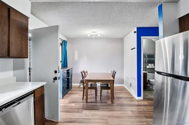 a kitchen with stainless steel appliances a refrigerator a stove a dining table and chairs