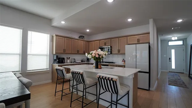 a kitchen with stainless steel appliances granite countertop a dining table chairs refrigerator and sink