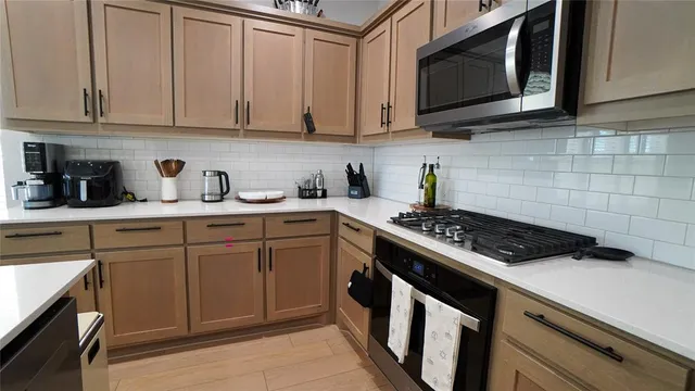 a kitchen with stainless steel appliances a stove a microwave a sink and cabinets