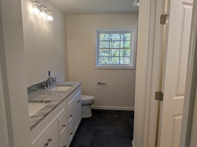 a bathroom with a granite countertop toilet and sink