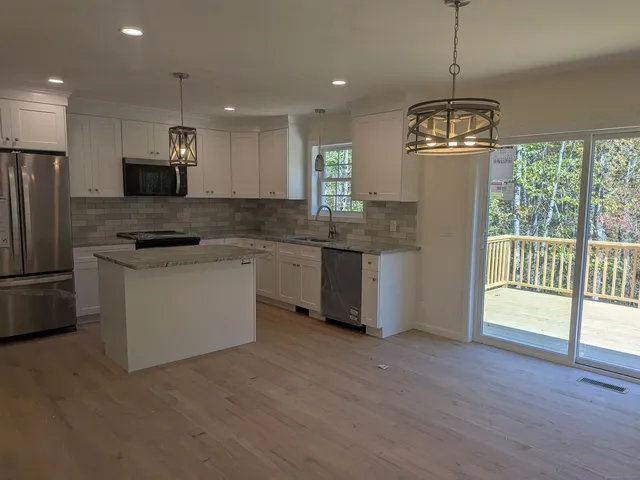 a kitchen with stainless steel appliances granite countertop a stove a sink a refrigerator and a microwave