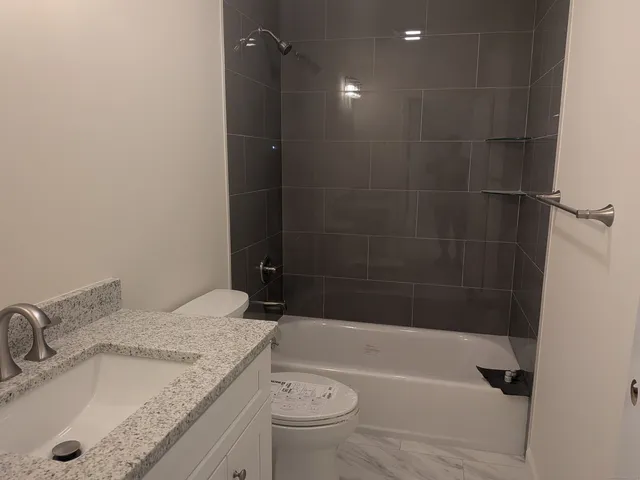 a bathroom with a granite countertop sink a toilet and bathtub