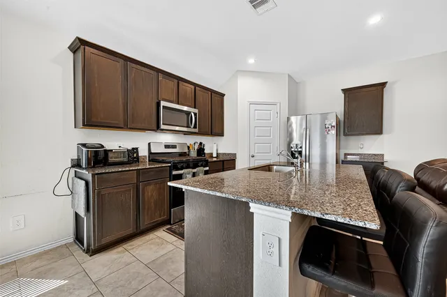 a kitchen with stainless steel appliances granite countertop a sink a stove and a refrigerator