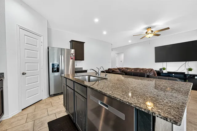 a kitchen with stainless steel appliances granite countertop a stove refrigerator and a sink
