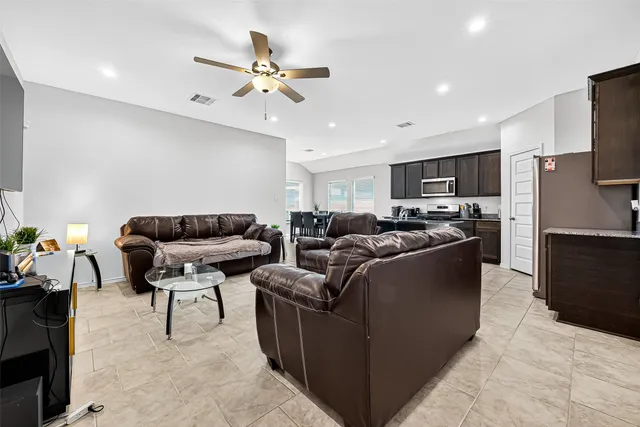 a living room with furniture a ceiling fan and a flat screen tv