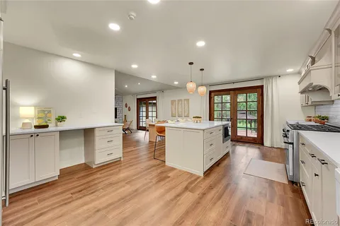 a large kitchen with stainless steel appliances refrigerator a stove top oven and a wooden floors