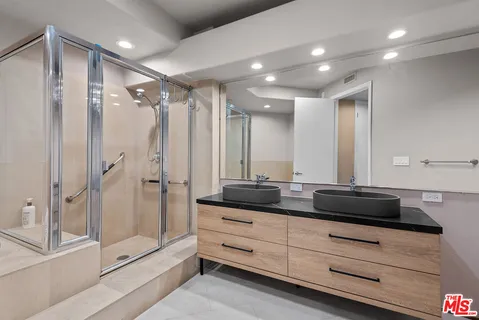 a bathroom with a double vanity sink and mirror with shower