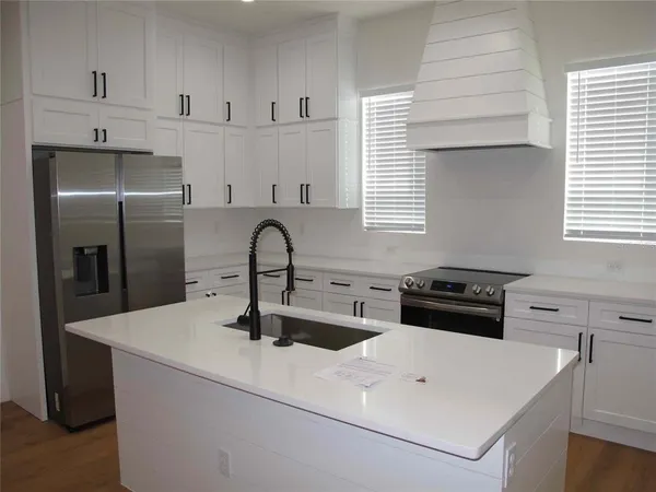 a kitchen with stainless steel appliances a sink a stove and white cabinets